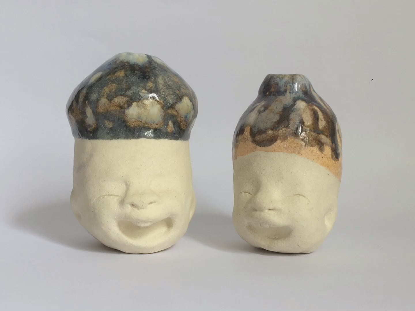 Two white figurative ceramic sculptures with glazed head.