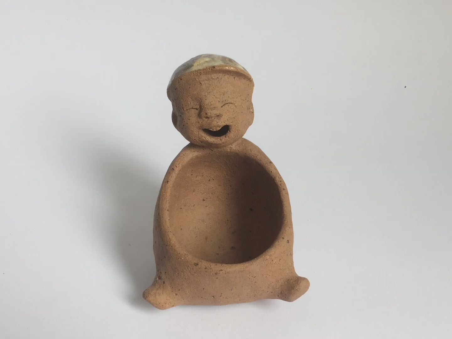 Brown unglazed ceramic object with speckle glazed accent on top.