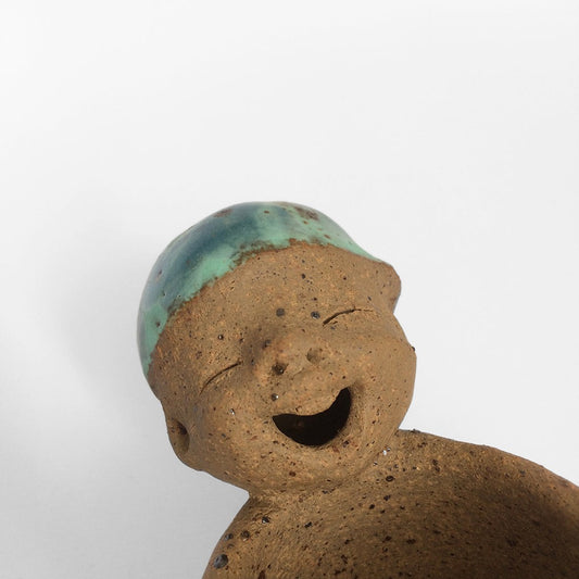 Brown unglazed figurative ceramic object with speckle glazed accent on top