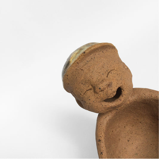 Brown unglazed ceramic object with speckle glazed accent on top.