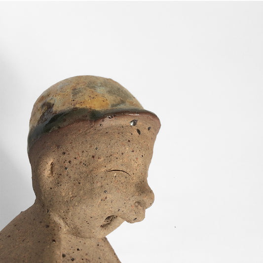 Brown unglazed figurative ceramic object with speckle glazed accent on top