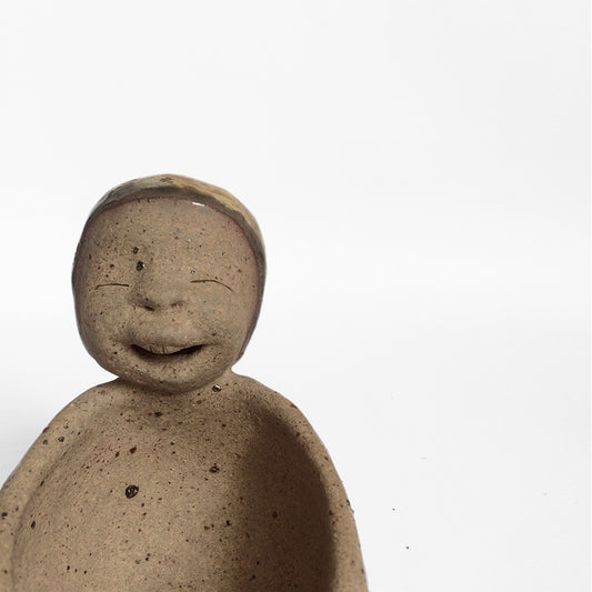 Brown unglazed figurative ceramic object with speckle glazed accent on top.