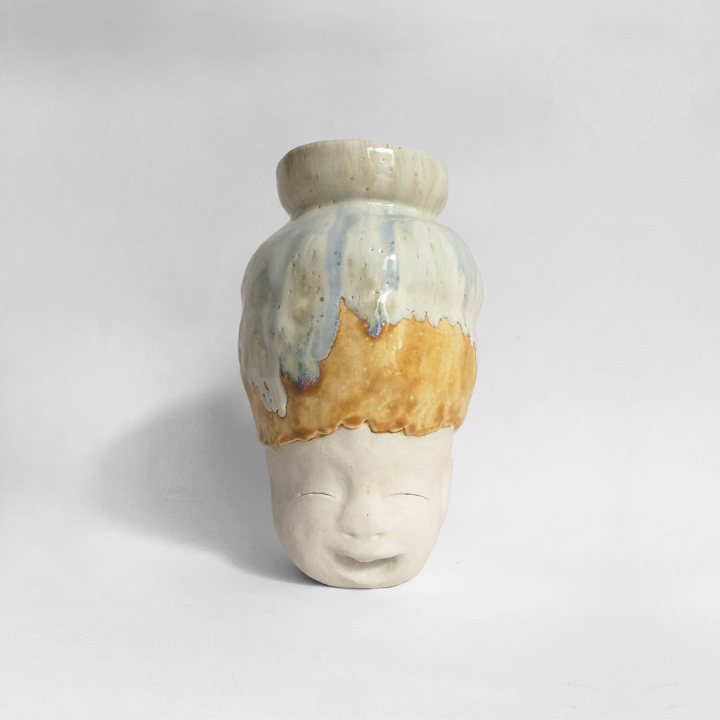 White figurative ceramic sculpture with white caramel glazed head facing front.