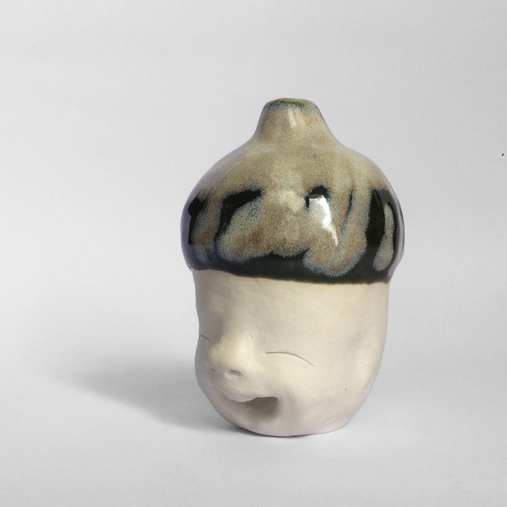 White figurative ceramic sculpture with mixed glazed head facing left.