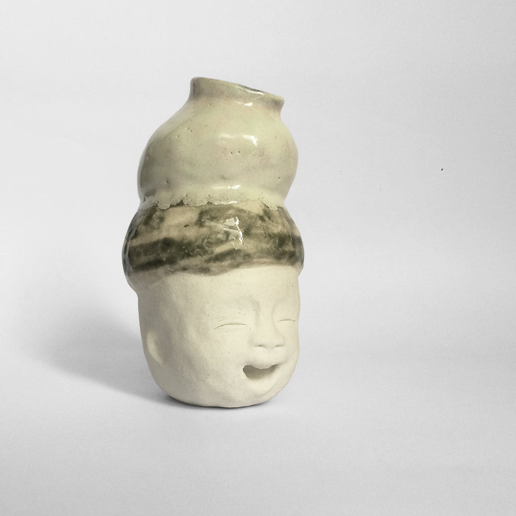 White figurative ceramic sculpture with mixed glazed head facing right.