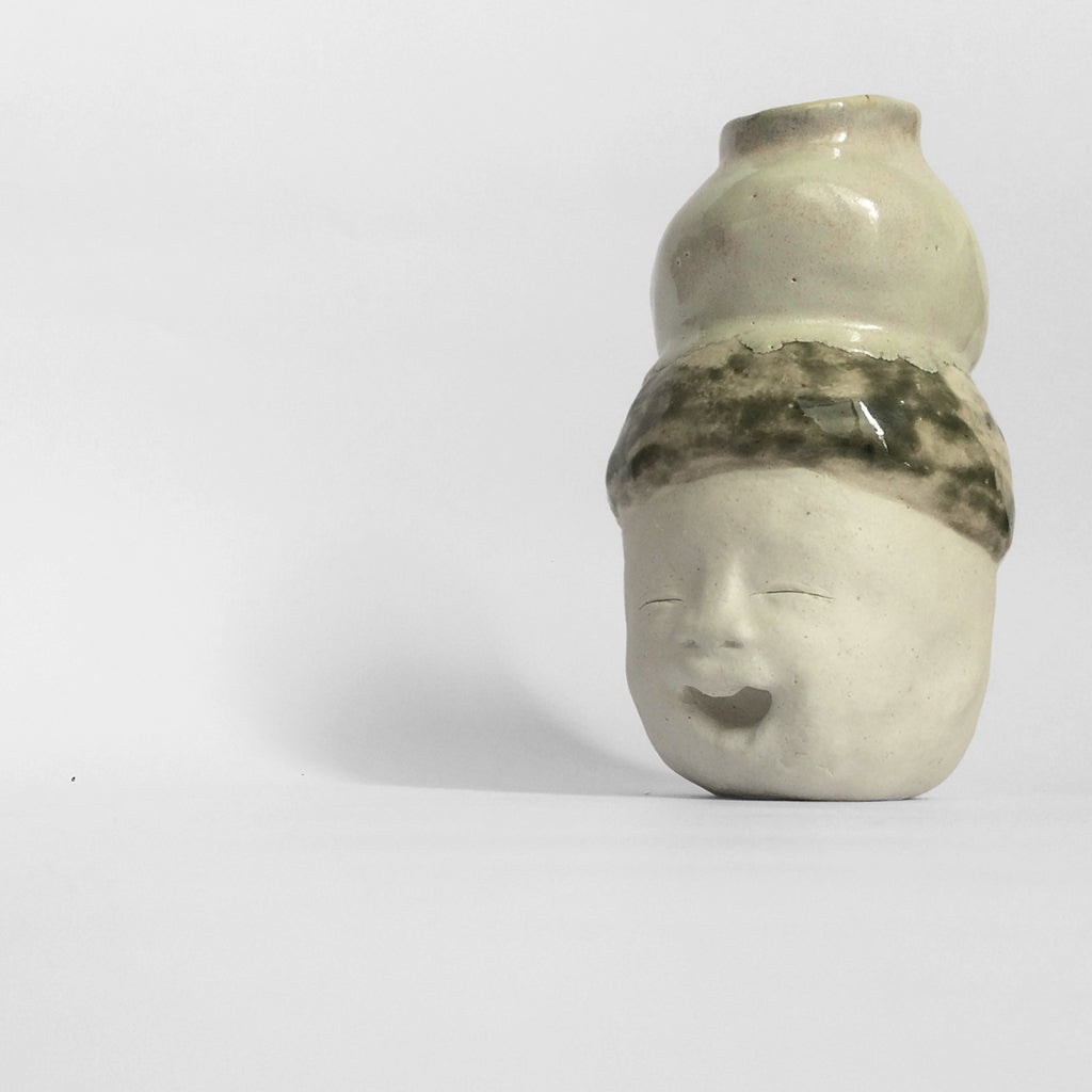 White figurative ceramic sculpture with mixed glazed head facing left.