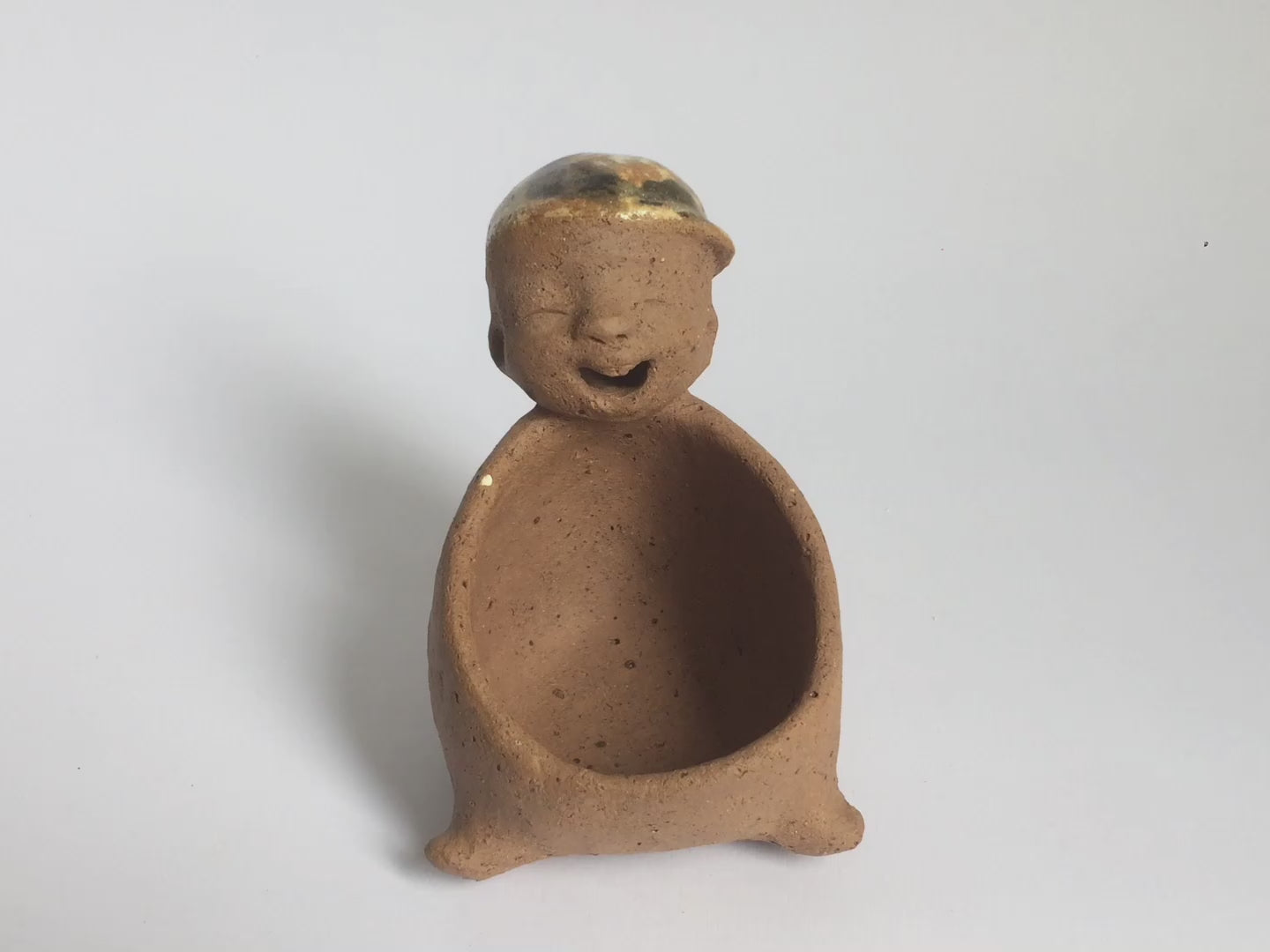 Video of brown unglazed figurative ceramic object with speckle glazed accent on top
