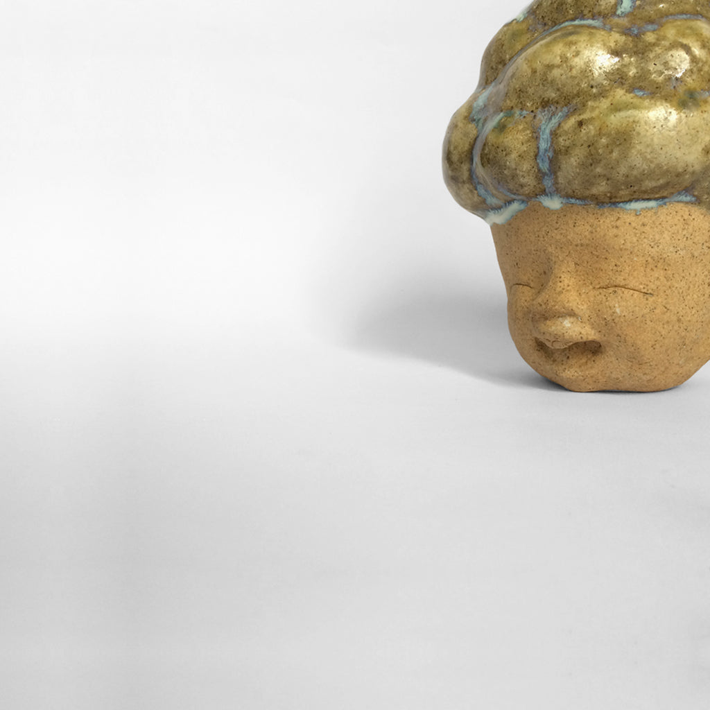 Brown figurative ceramic sculpture with brown glazed head facing left.