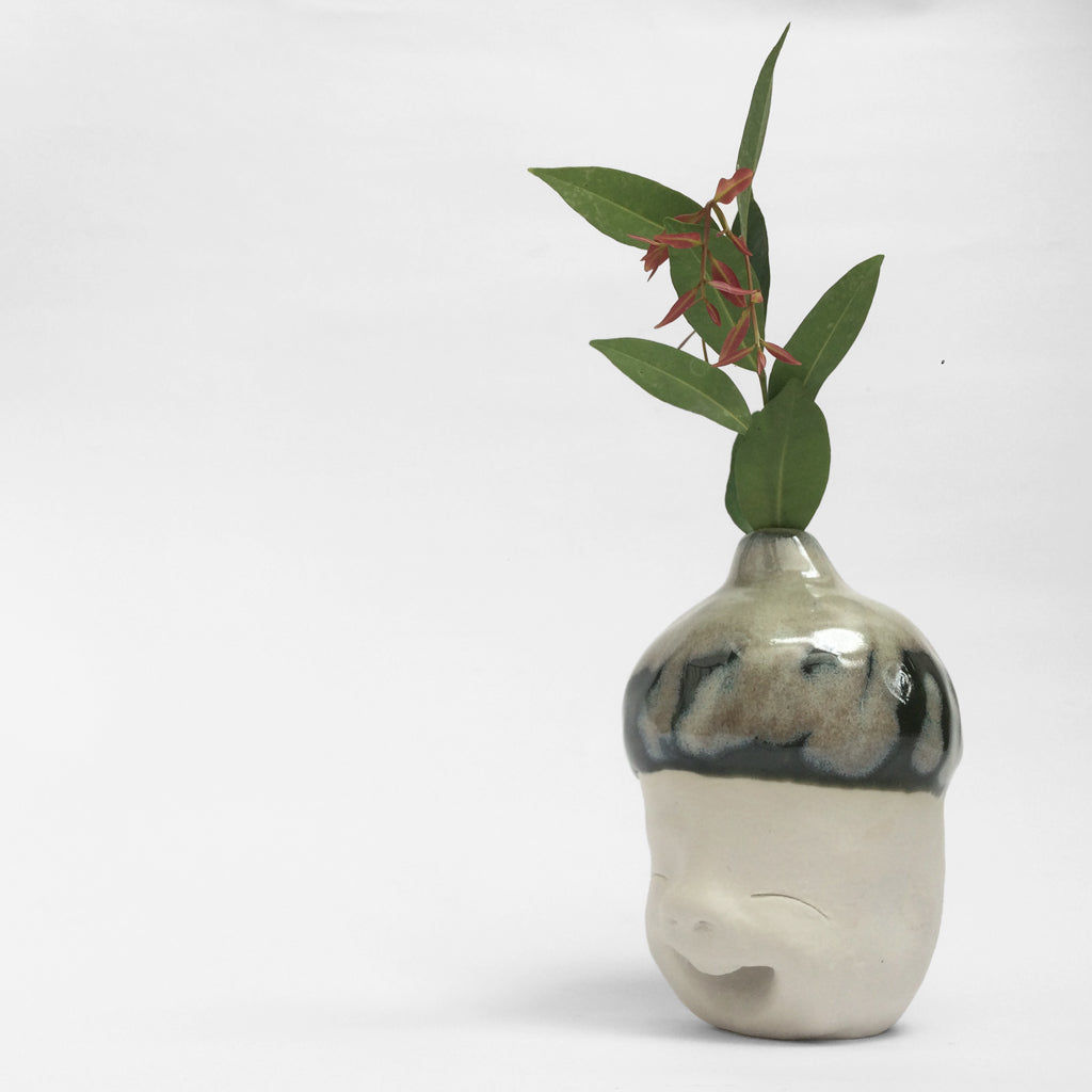 White figurative ceramic sculpture with mixed glazed head facing left.