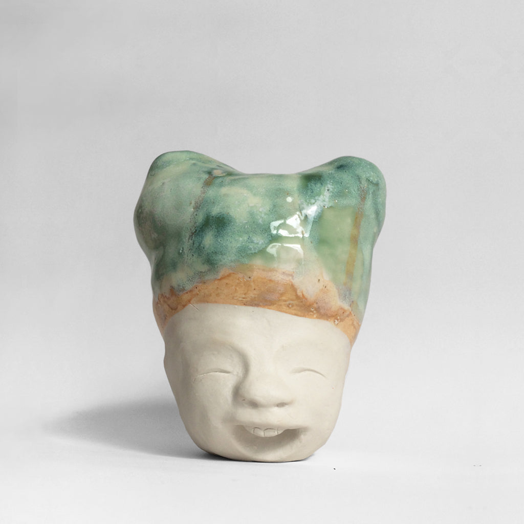 White figurative sculpture with mixed glazed head facing front.