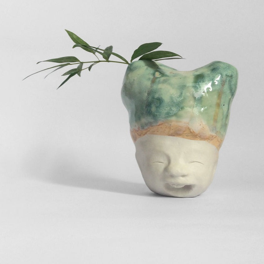 White figurative sculpture with mixed glazed head facing front.