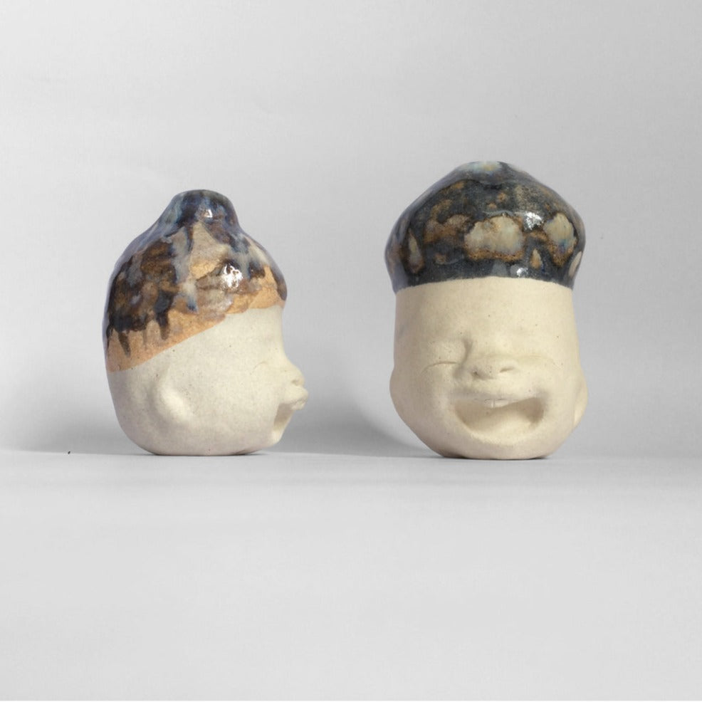 two white figurative ceramic sculptures with dark blue glazed head facing right and front.