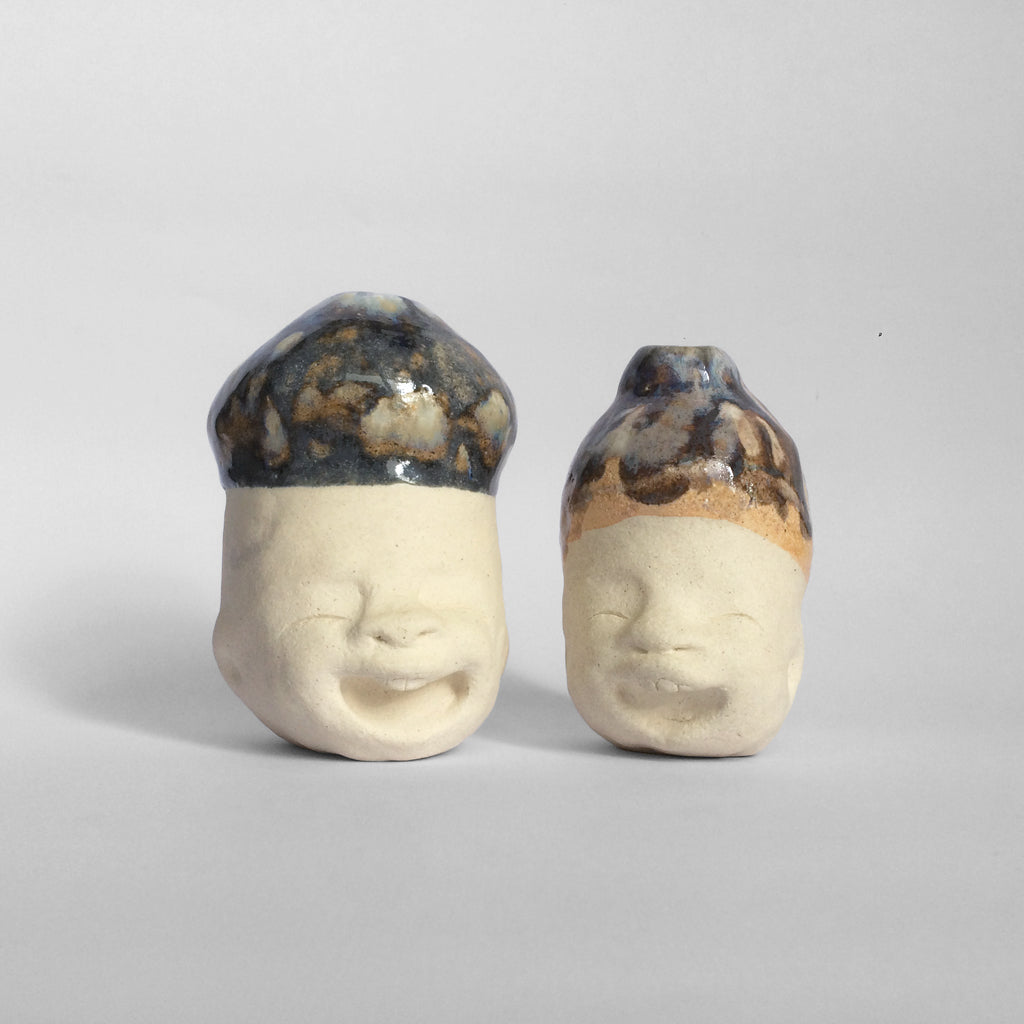 Two white figurative ceramic sculptures  facing front with dark bule glazed head.