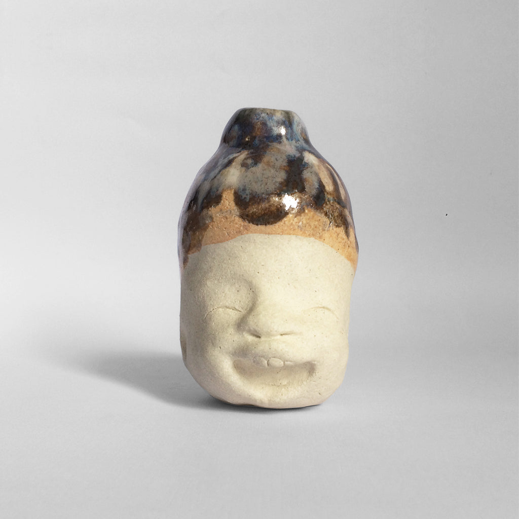 White figurative ceramic sculpture with dark blue and orange glazed head.