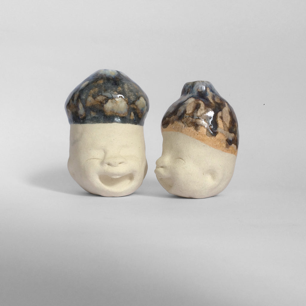 Two white figurative ceramic sculptures with dark blue glazed head.