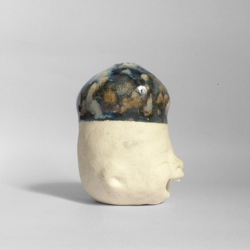White figurative ceramic sculpture with dark blue glazed head facing sideways.