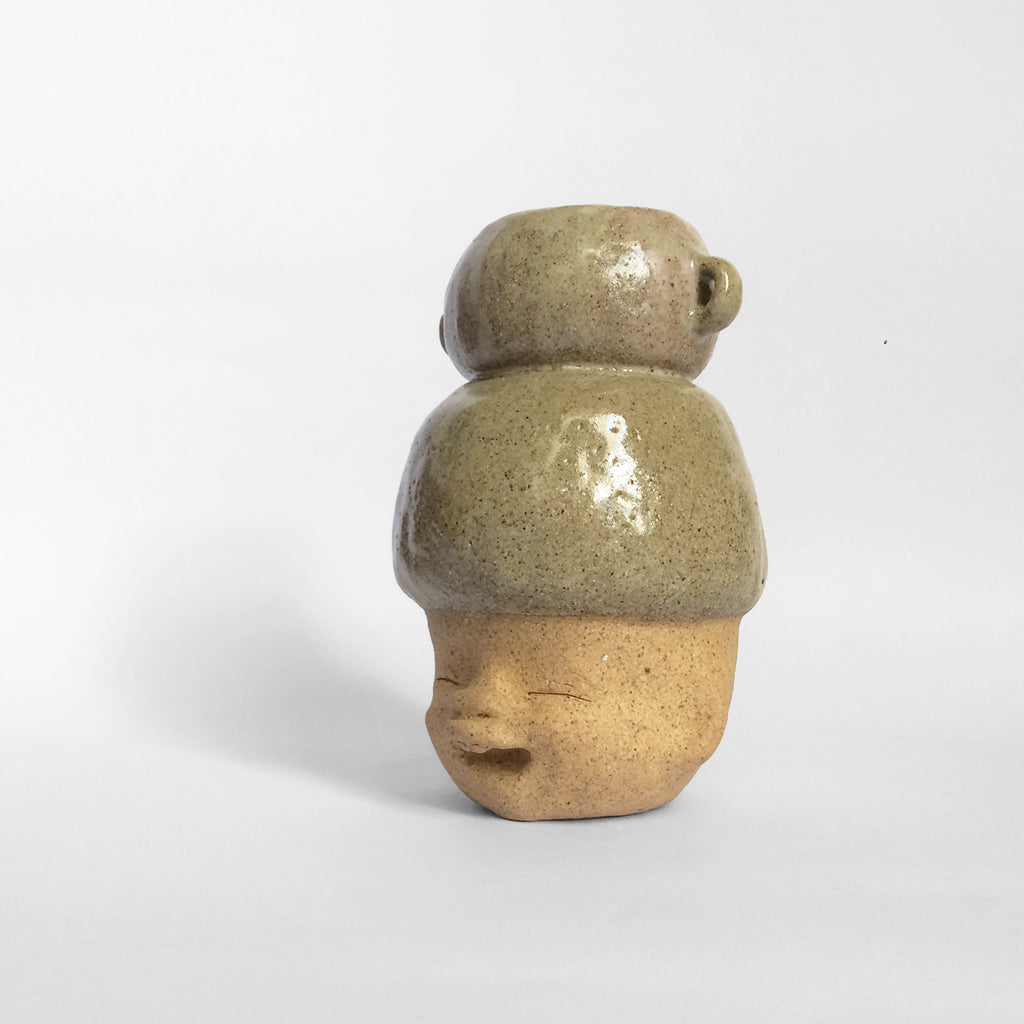 Brown figurative ceramic sculpture with greenish brown glazed head facing left.
