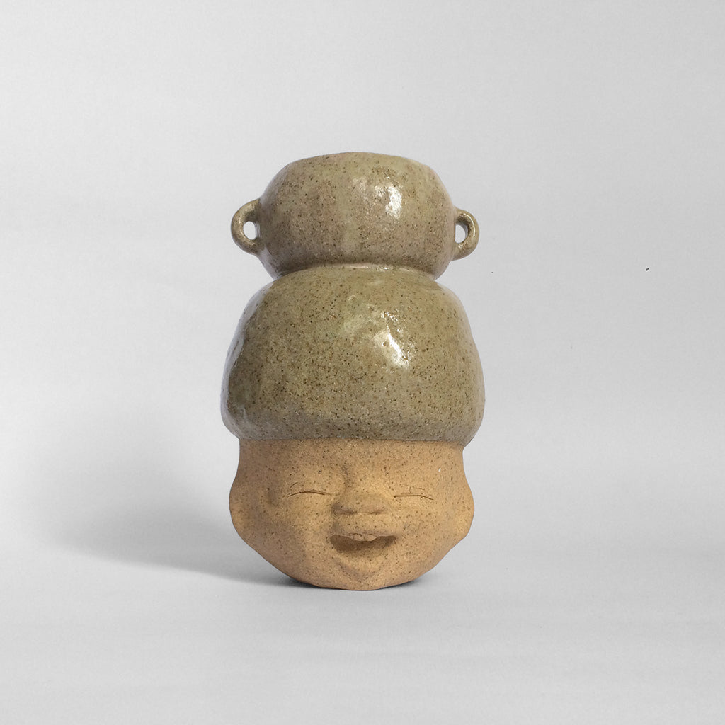 Brown figurative ceramic sculpture with greenish brown glazed head facing front.