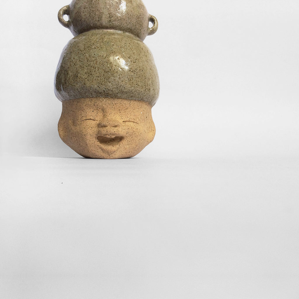 Brown figurative ceramic sculpture with greenish brown glazed head facing front.