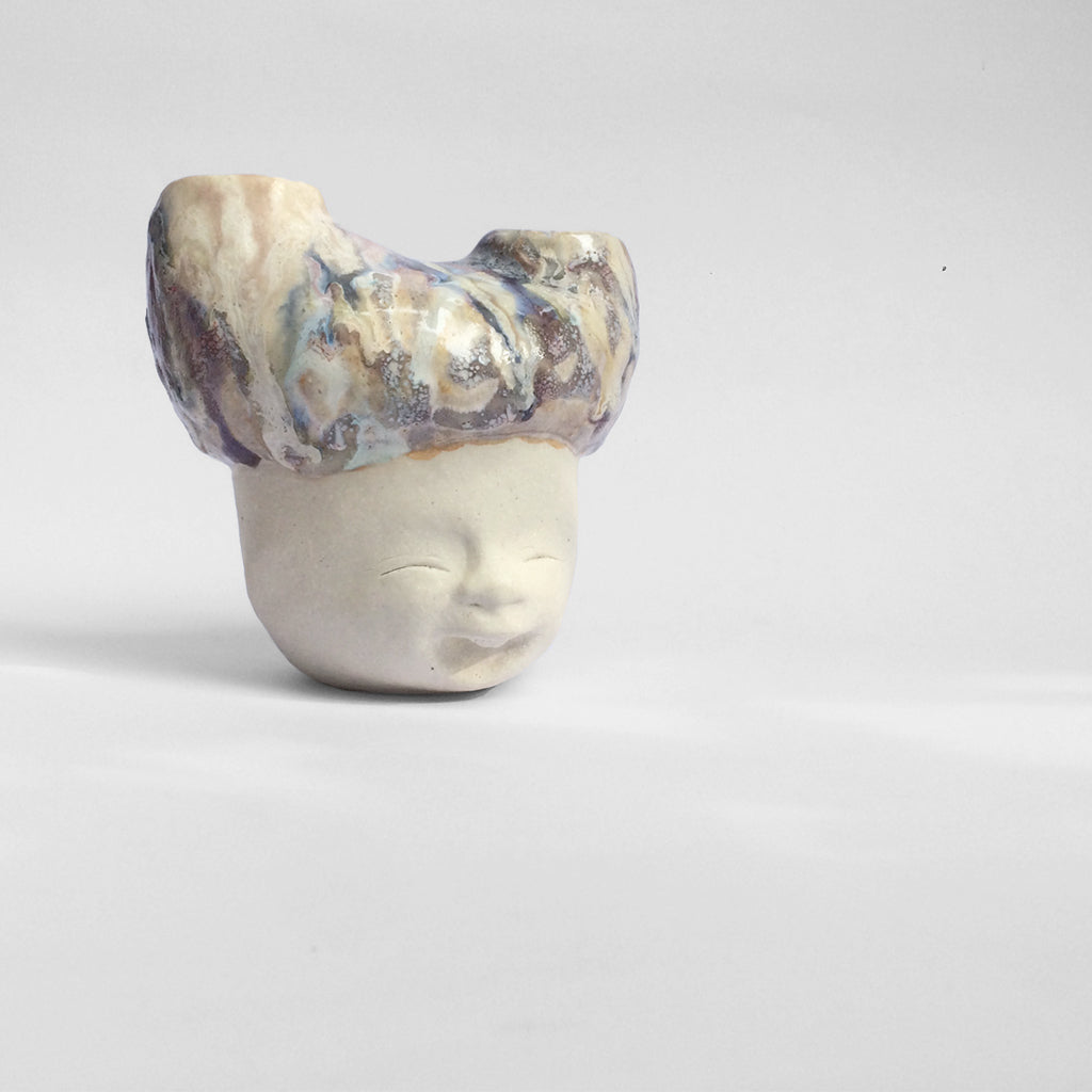 White figurative ceramic sculpture with abstract purple glazed head  facing right.