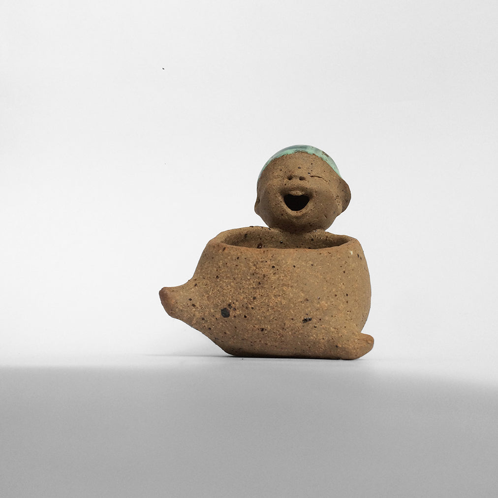 Brown unglazed figurative ceramic object with blue glazed hat facing front