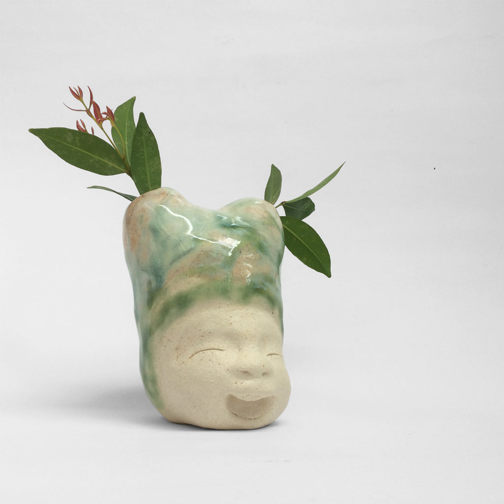 White unglazed figurative ceramic sculpture with green green glazed head.