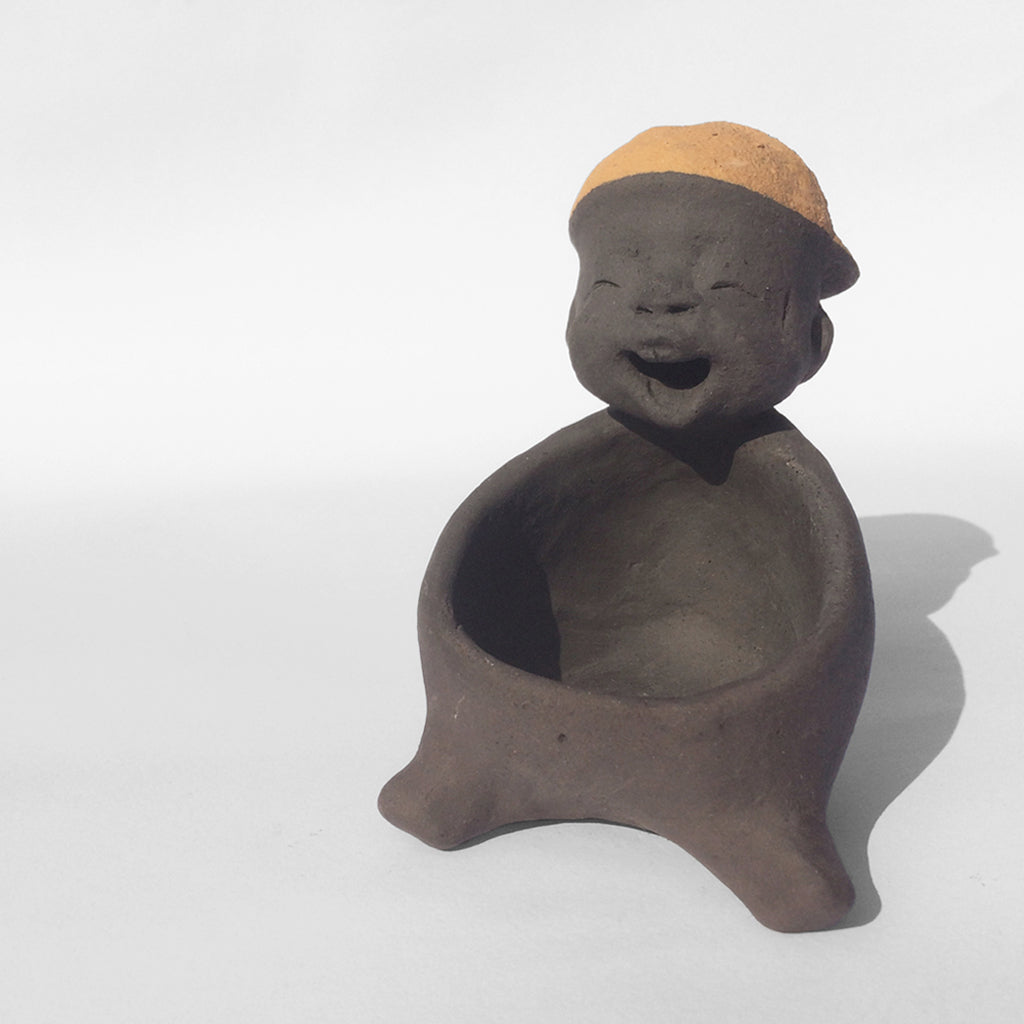 Dark grey ceramic figurine with orange cap.