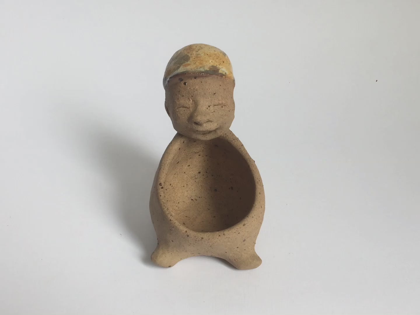 Video of brown unglazed figurative ceramic object with speckle glazed accent on top