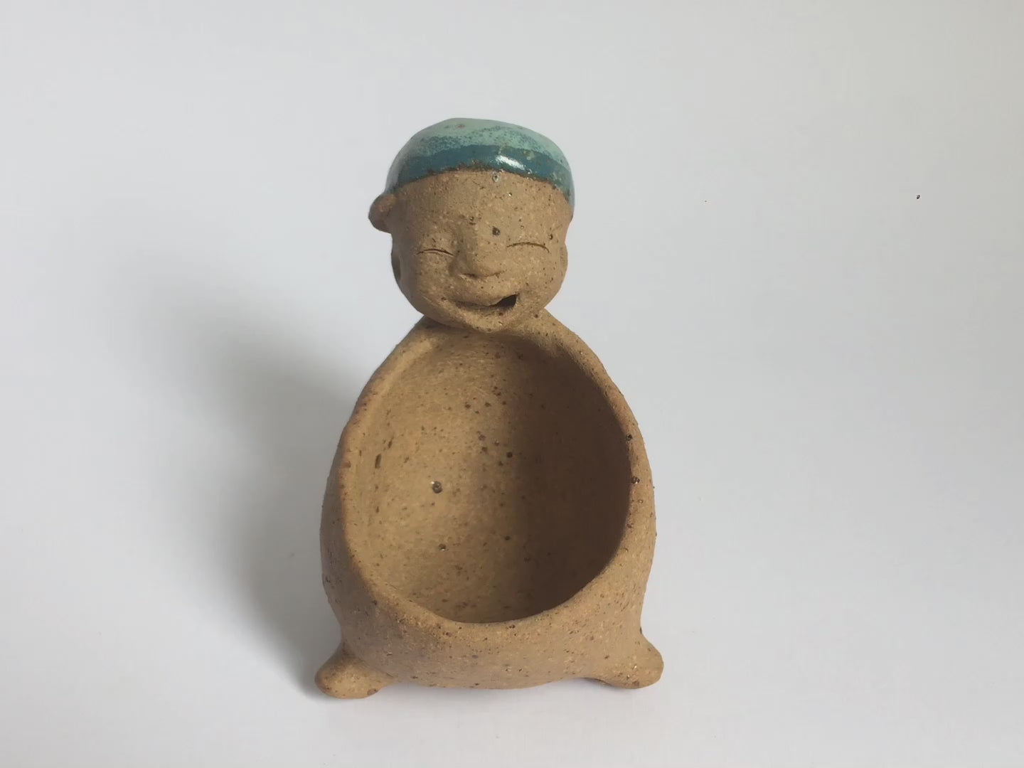 Video of brown unglazed figurative ceramic object with blue glazed accent on top