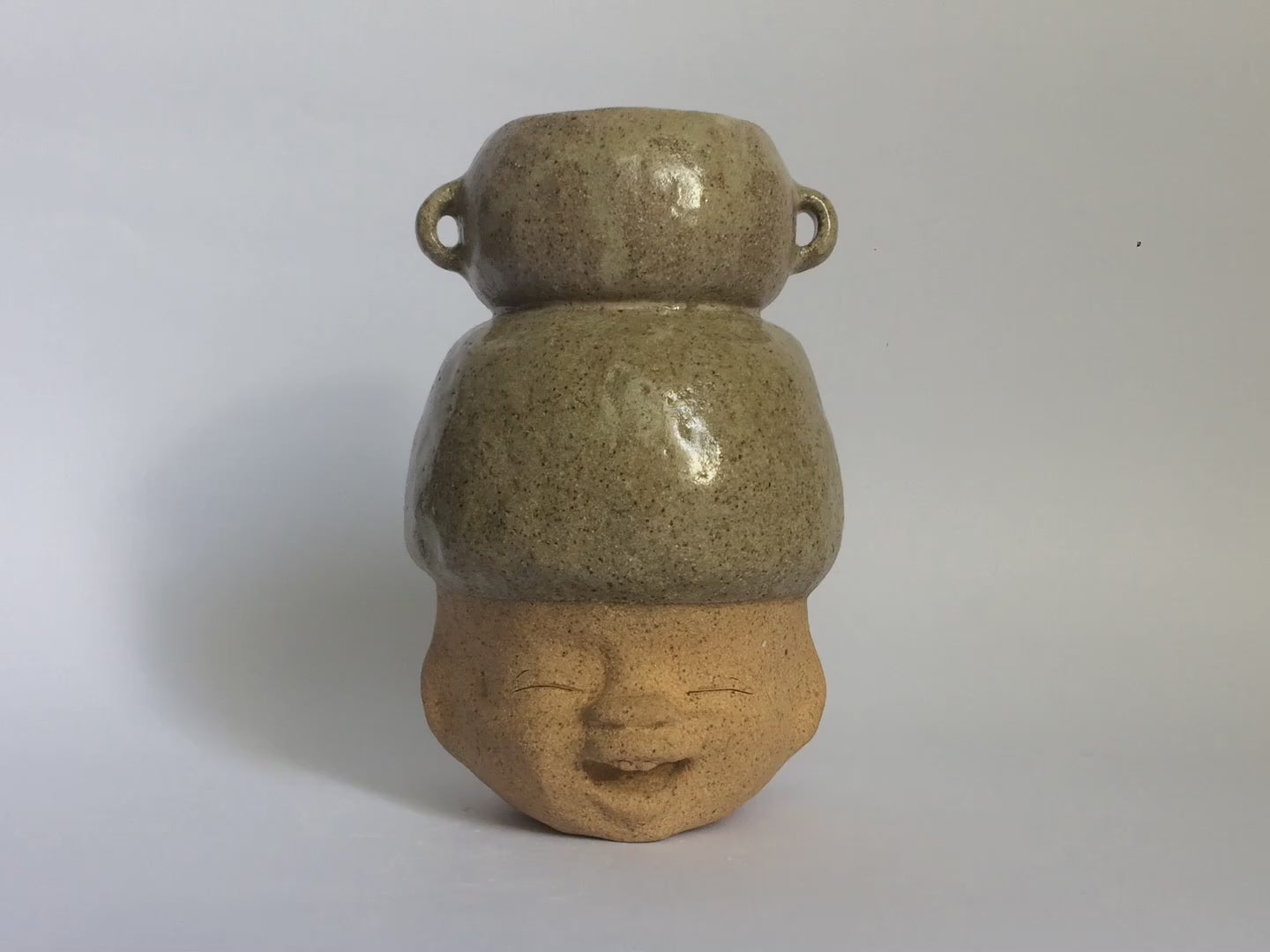 Brown figurative ceramic sculpture with greenish brown glazed head 360 video.