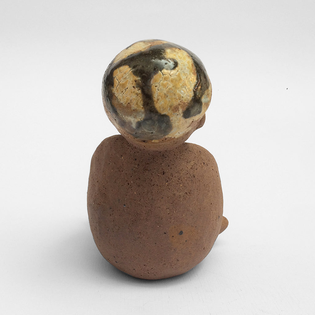 Brown unglazed ceramic object with speckle glazed accent on top.
