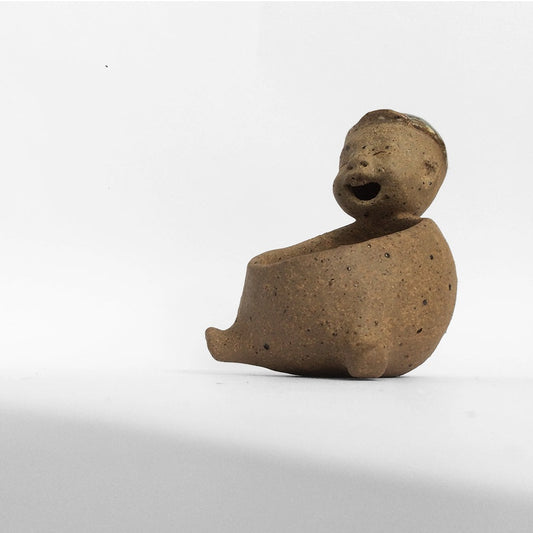 Brown unglazed figurative ceramic object with speckle glazed accent on top