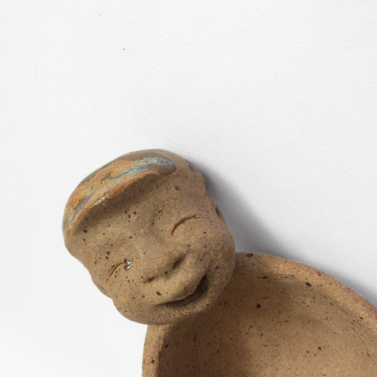 Brown unglazed figurative ceramic object with speckle glazed accent on top