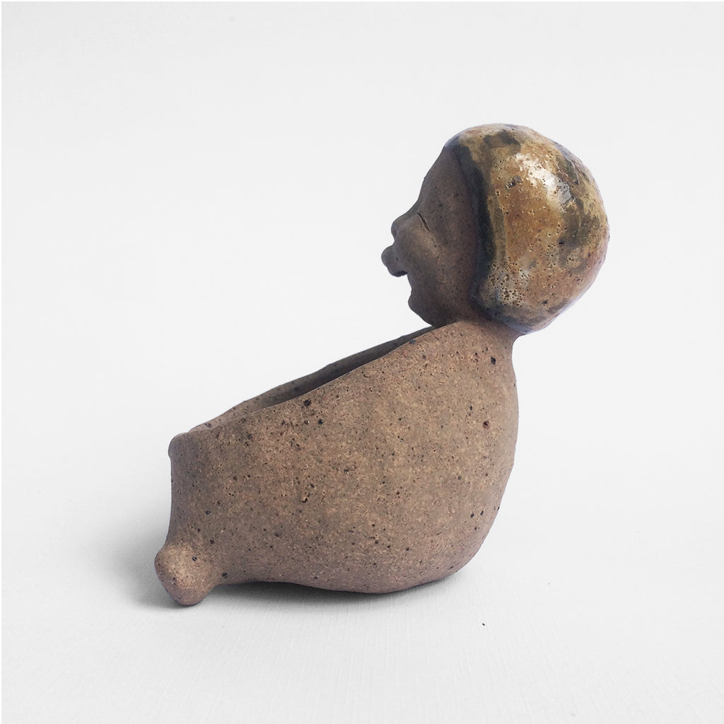 Brown unglazed figurative ceramic object with speckle glazed accent on top.
