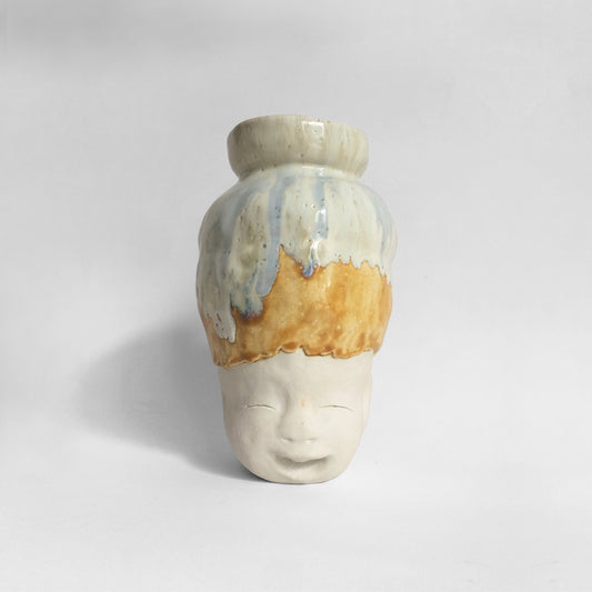 White figurative ceramic sculpture with white caramel glazed head facing front.