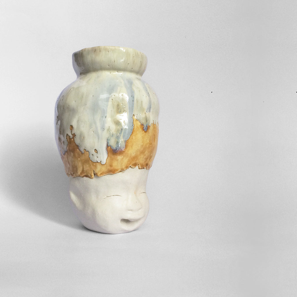 White figurative ceramic sculpture with white caramel glazed head facing right.
