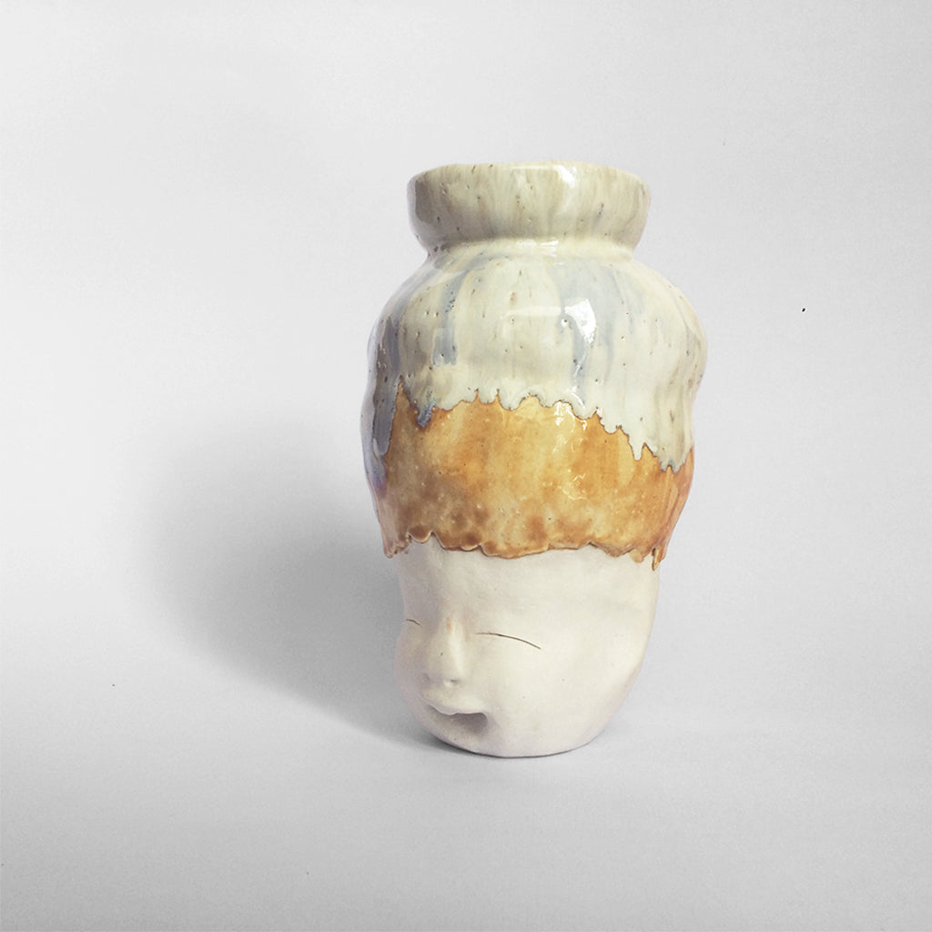 White figurative ceramic sculpture with white caramel glazed head facing left.