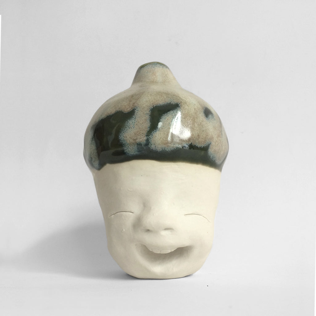 Figurative white ceramic sculpture with mixed glazed head facing front.