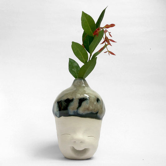 Figurative white ceramic sculpture with mixed glazed head facing front.