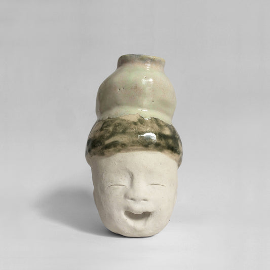 White figurative ceramic sculpture with mixed glazed head facing front.