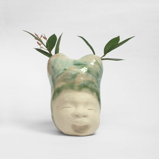 White figurative ceramic sculpture with mixed glazed head facing front.