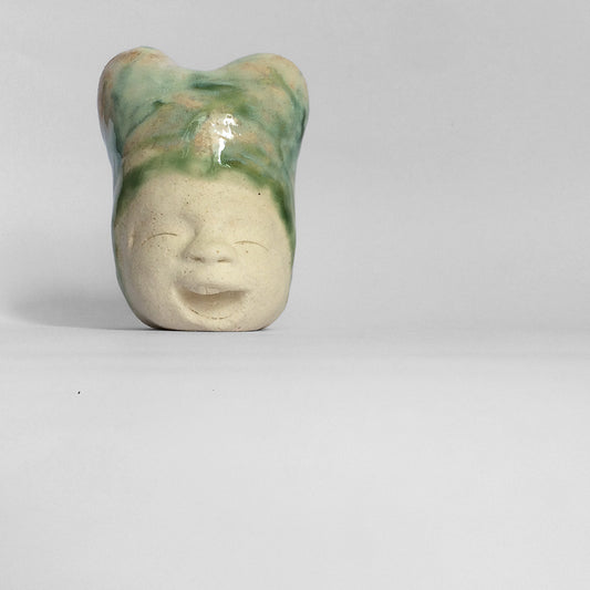 White figurative ceramic sculpture with mixed glazed head facing front.