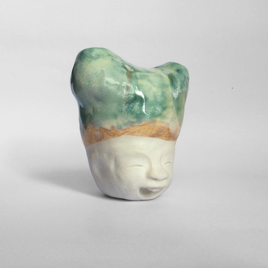 White figurative sculpture with mixed glazed head facing right.