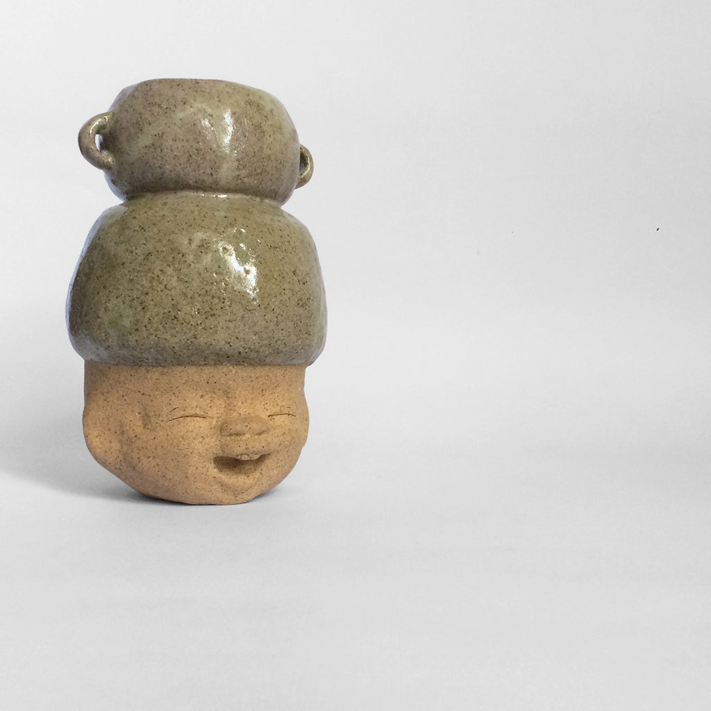 Brown figurative ceramic sculpture with greenish brown glazed head facing right.