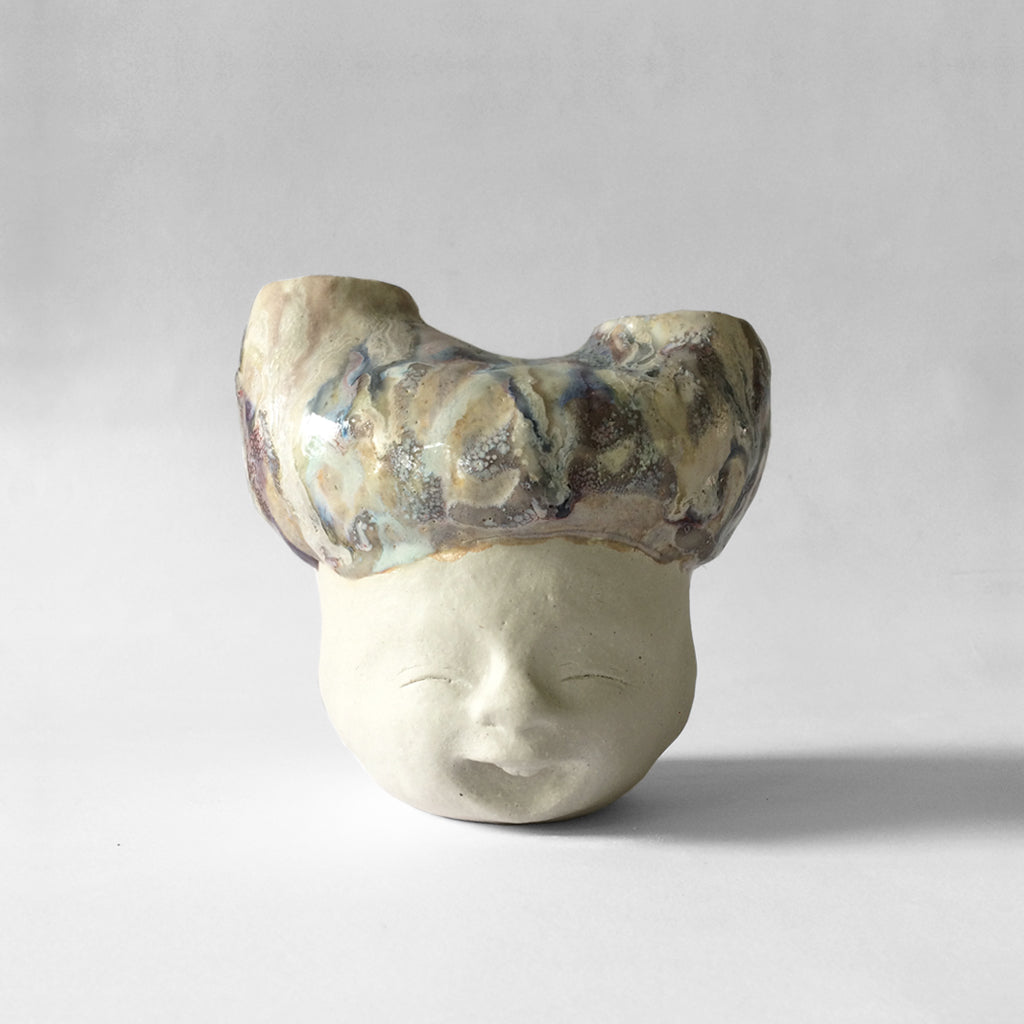 White figurative ceramic sculpture with abstract purple glazed head  facing front.