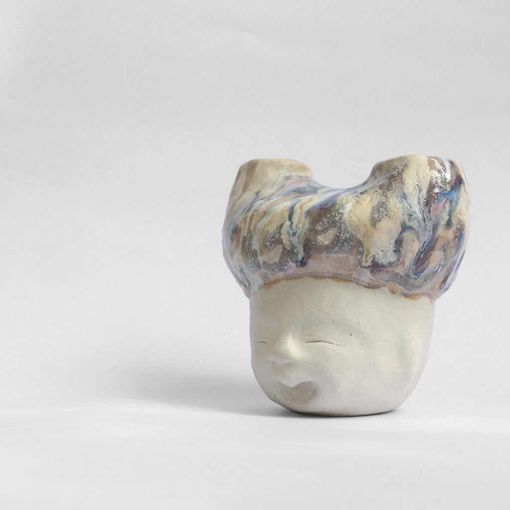 White figurative ceramic sculpture with abstract purple glazed head  facing left.