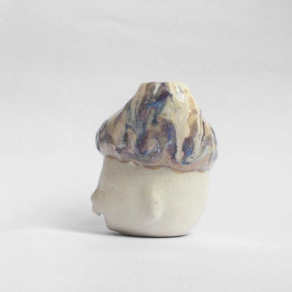 White figurative ceramic sculpture with abstract purple glazed head  facing right.